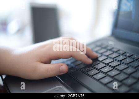 Concept idea of a child with hands on the keyboard pressing the keys of the keyboard while playing a game Stock Photo