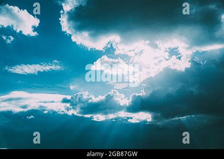 Sunrays Sunray Shine Through Dark Clouds In Cloudy Blue Sky. Natural Background. Natural Sky Backdrop Weather Conditions. Cloudy Sky With Fluffy Stock Photo