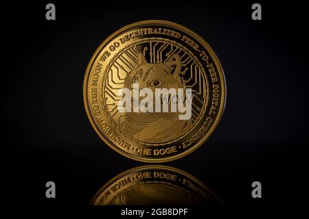 DOGE Cryptocurrency physical coin placed on reflective surface in the dark background Stock Photo