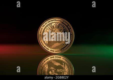 Doge cryptocurrency physical coin placed on reflective surface and lit with green and red lights Stock Photo