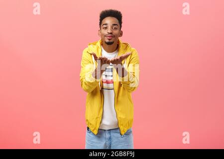 Blowing you sweet kisses. Cute and handsome stylish man with beard and afro hairstyle bending towards camera folding lips and smiling sending mwah Stock Photo