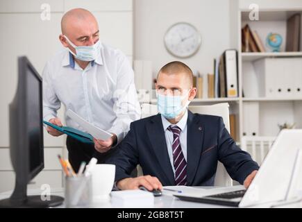 Two businessmen in fase masks discussing new ideas Stock Photo