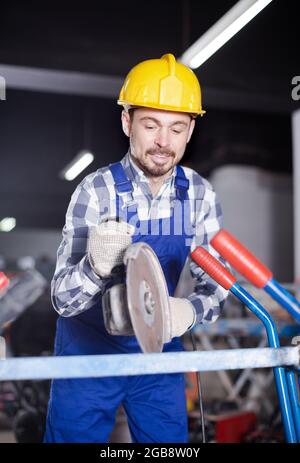 Young positive male using angle grinder for construction Stock Photo