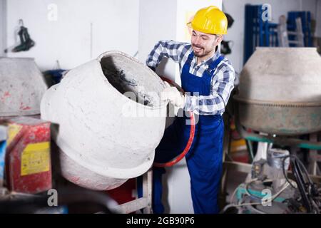 Smiling man using concrete mixer for construction Stock Photo