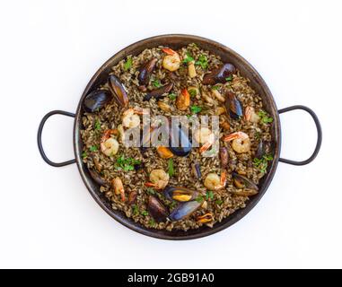 Black paella with rice, shrimps, mussels and squid ink on white background Stock Photo