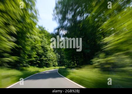 View through windscreen of moving car on winding country road, Weserbergland, Lower Saxony, Germany Stock Photo