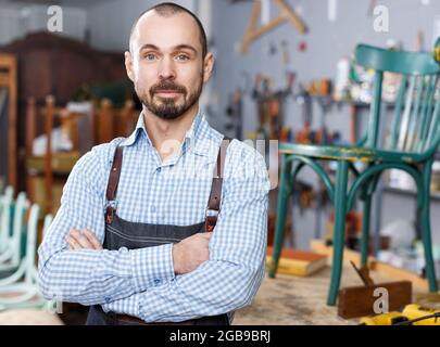 Carpenter standing in furniture repair shop Stock Photo