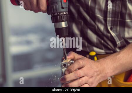 Man working making holes in board with drill during process of furniture manufacturing Stock Photo