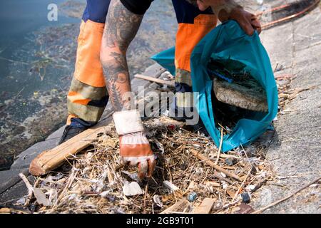 Emden, Germany. 09th June, 2021. Björn Fuhlendorf, NPorts employee, collects rubbish that has washed up at the port. Several cities in Lower Saxony are planning to equip their harbours with the so-called marine litter bins in the near future. A submersible pump underneath a basket permanently sucks in water. Flotsam floating on the water surface nearby is sucked in and falls into the collection net. The water flows back into the harbour basin. (to dpa-KORR.: 'Buckets with suction: How floating trash cans rid harbors of plastic') Credit: Sina Schuldt/dpa/Alamy Live News Stock Photo