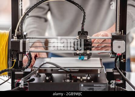 Man working with 3D printer on design project in lab. Closeup view of equipment Stock Photo