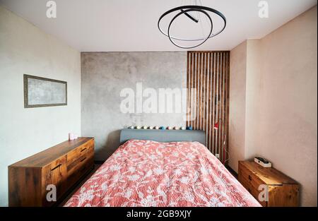 Front view of modern apartment in soft warm colors, big bedroom and stylish brown bedside tables. Concept of modern interior spacious bedroom with beautiful furniture. Stock Photo