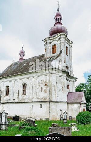 Puste Zibridovice,Czech Republic - July 12,2021. White old baroque Church of Saint Mary Magdalene with bell tower and cemetery in small Czech village Stock Photo