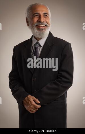 AN OLD MAN IN FORMAL WEAR HAPPILY STANDING AND SMILING Stock Photo