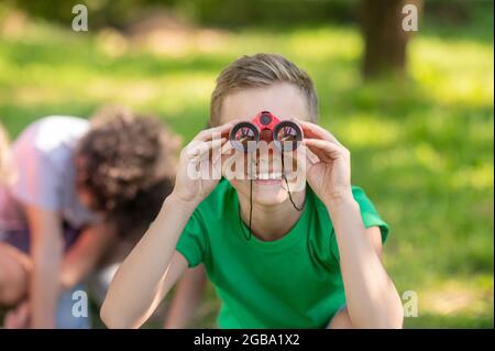 Boy looking through binoculars in nature Stock Photo