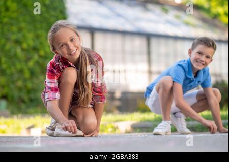 Girl and boy drawing with crayons in park Stock Photo