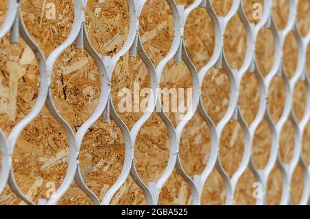 Repeating circular Metal honeycomb against a plywood panel in a receding perspective. An old rusted iron wall or fence. Architecture. Selective focus. Stock Photo