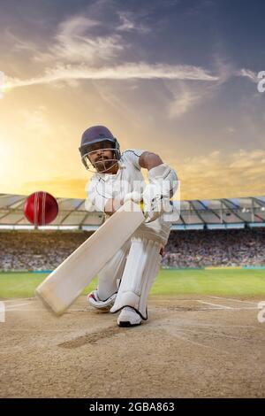 Cricketer batsman hitting a shot during a match on the pitch Stock Photo