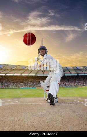 Cricketer batsman hitting a shot during a match on the pitch Stock Photo