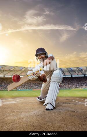 Cricketer batsman hitting a shot during a match on the pitch Stock Photo