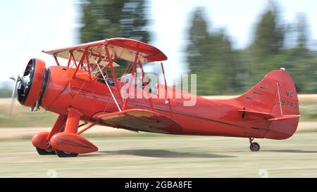 Ferrara Italy JUNE, 27, 2021 Vintage red biplane takes off from a grass airfield. Panning picture.. WACO UPF7 Stock Photo