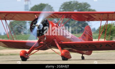 Ferrara Italy JUNE, 27, 2021 Red vintage biplane with radial engine and propeller rotating. WACO UPF7 Stock Photo