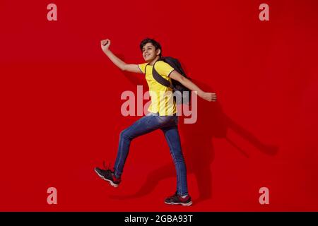 A CHEERFUL TEENAGE BOY HAPPILY POSING WEARING SCHOOL BAG Stock Photo