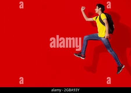 AN EXCITED TEENAGER JUMPING AND POSING WHILE WEARING SCHOOL BAG Stock Photo