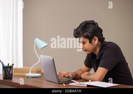 A TEENAGE BOY STUDYING ON LAPTOP Stock Photo