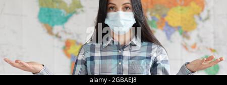 Portrait of woman in medical protective mask against background of world map Stock Photo