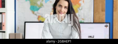 Woman leader stands with her hands resting on table in her office Stock Photo