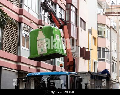 Local council truck emptying container for glass/bottles only for recycling in Spain Stock Photo