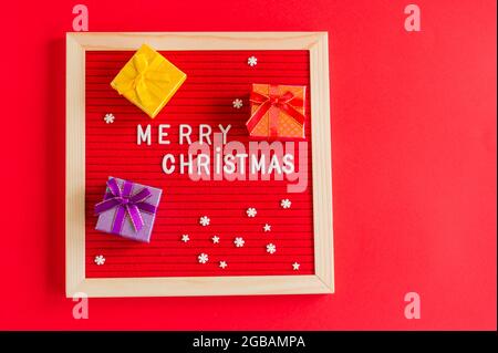 merry christmas festive background with red letter board and small gift boxes and copy space. Stock Photo