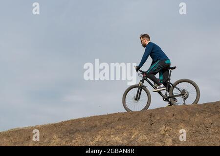 Bearded mountain bicyclist rides mountains Stock Photo
