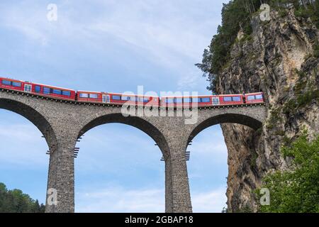 Filisur, Switzerland - June 17, 2021: A train is crossing a famous Landwasser viaduct nearby Filisur town in the swiss alps Stock Photo