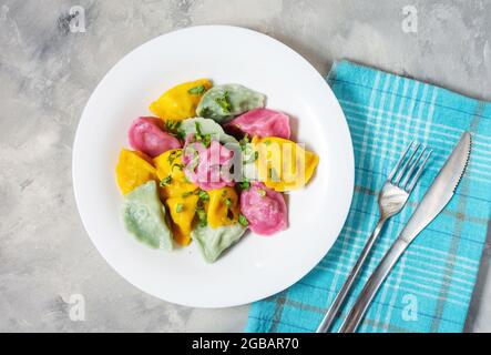 Multi colored dumplings from color dough stuffed with meat on concrete background. top view Stock Photo