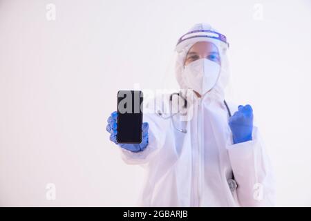 A health worker in PPE kit holding a mobile phone. Stock Photo