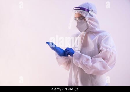 A health worker in PPE kit wearing gloves. Stock Photo