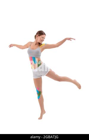 Woman showing kinesio tapes taped to her body. Full-length portrait of woman with Bright medical kinesio tapes Stock Photo