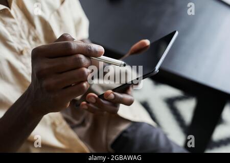 Close-up of African man holding pen and typing on touch screen of digital tablet during his online work Stock Photo