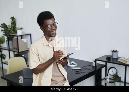 Successful African businessman typing on digital tablet and working online while sitting at office Stock Photo