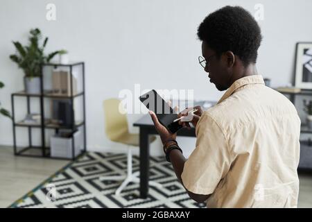 Rear view of African businessman using pen and typing on digital tablet Stock Photo