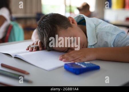Caucasian boy sleeping on his desk in the class at school Stock Photo