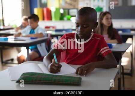 African american boy studying while sitting on his desk in the class at school Stock Photo