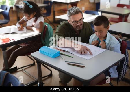 Caucasian male teacher teaching caucasian boy in the class at school Stock Photo