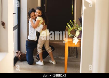 Happy mixed race mother and daughter hugging in hallway Stock Photo