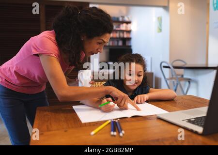 Young mom helping her little son with study, they sitting at desk and ...