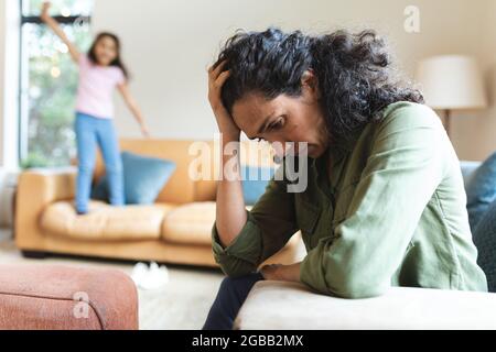 Tired mixed race mother sitting on sofa, having headache Stock Photo