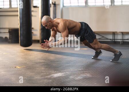 Strong caucasian man exercising at gym, doing push-ups Stock Photo