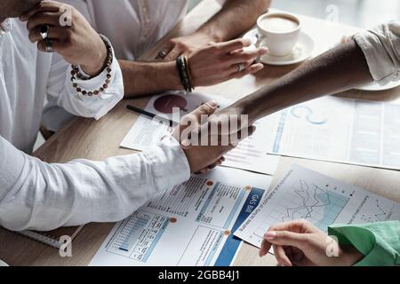 Two successful Muslim businessmen shaking hands over financial documents by workplace Stock Photo