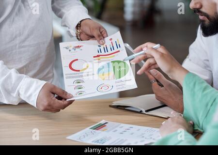 Hands of economists discussing financial document by workplace at meeting Stock Photo